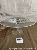 Full view of clear glass server plate showing flat round surface on top with pedestal base.