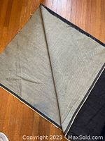 Full view of denim fabric bolt unfolded showing front and back sides with raw edges on hardwood floor.