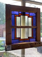 Full view of the vintage stained glass panel hanging, showing the geometric stained glass design and pine wood frame.