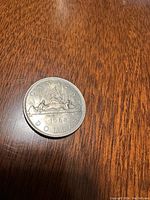 Reverse side of 1968 Canadian silver dollar coin showing horse-drawn toboggan and year.