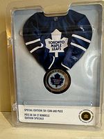 Front of the packaging showing a navy blue Toronto Maple Leafs jersey insert with the coin centered below it. The coin face features the team logo and is encased in the display puck.