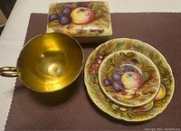 Overall view of fruit cup, saucer and trinket dish on brown cloth