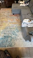 Rug positioned under sofa showing overall abstract color pattern and size relative to furniture