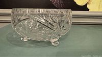 Side view of the crystal footed bowl showing the three rounded feet and intricate cut designs on the bowl's body.