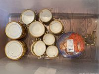 Top view of stacked cups and saucers along with gold rim bouillon cups and a decorative plate.