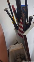 Multiple baseball bats of different colors and materials standing upright with an American flag among them.