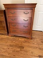 Front view of the four-drawer wooden dresser with medium brown finish and two metal handles per drawer.