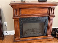 Full front view of the electric fireplace showing wooden mantel and black trim.