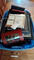 Large plastic tote filled with assorted picture frames of various materials, colors, and sizes.
