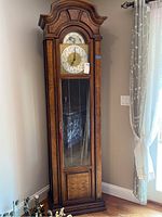 Full view of the grandfather clock showing wooden case, glass front, and pendulum area