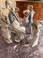 Five figurines together on marble tabletop showing overall lot contents