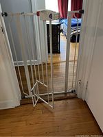 Full view of one extra tall white metal pet gate installed in a doorway, featuring an additional small pet door at the bottom.