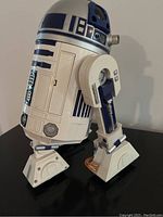 White and blue R2-D2 droid figure standing upright on black surface