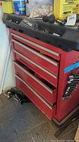 Full view of red Craftsman rolling tool chest showing five drawers, black top with storage compartments, and visible wear and oxidation.