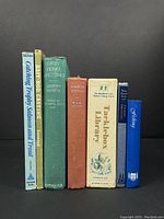 Seven fishing and angling books standing upright against black background, showing spine titles and covers.