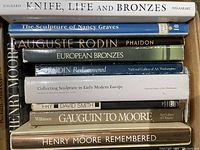 Photo of eleven sculpture art books stacked horizontally in a box, showing titles focused on Rodin, Henry Moore, Nancy Graves and European bronzes.