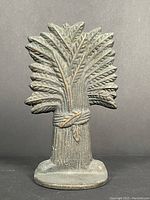 Front view of antique cast iron wheat sheaf door stop showing detailed wheat stalks and base.