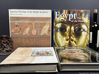 Four Egyptian art and history books arranged standing and lying down, showing their front covers with art and historical themes.