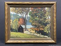 Full view of framed fall landscape painting showing houses, trees with autumn foliage, and stone wall.
