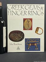 Front cover of 'Greek Gems and Finger Rings' book showing title, author's name, and color images of ancient gems and rings.