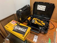 Lot overview showing DW321 jig saw in case, boxed DW6901 parallel fence, and cordless drill case on a wood surface.