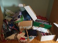 Large pile of assorted fabric pieces in various boxes and bags, showing colorful and patterned textiles.