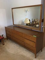 Full view of the wood dresser with attached framed mirror, showing the front and side angles.