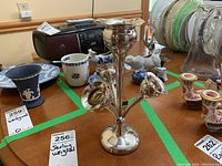 View of the tall sterling silver weighted candle holder alongside other items on a table, showing polished surface and shape