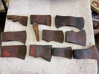 Photo showing all 10 antique axe heads laid out on table, varying in size, shape and wear