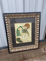 Full view of framed print showing the artwork of a seated woman and child with ornate gold and black frame