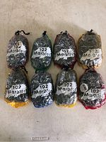 Eight sealed plastic bags each containing 102 vintage glass marbles, arranged in two rows on a flat surface.