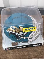 Front angle of Jacksonville Jaguars mini helmet in display case showing team logo and visible autograph on top.