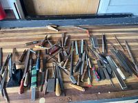 Overhead photo showing the entire variety of files, rasps, chisels, and miscellaneous hand tools laid out on a wooden surface.
