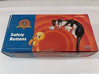 Closed Looney Tunes box with Sylvester and Tweety art and Safety Buttons label, indicating 6 dozen assorted buttons inside.