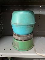 Front view of vintage electric rock tumbler showing turquoise drum on green base with unplugged cord.