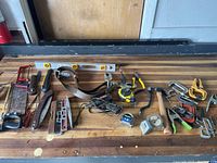 Wide view of assorted tools including levels, clamps, hammer, tapes, pliers, tool belt, and metal spirit level