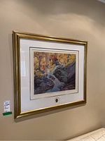 Framed artwork hung on wall, gold-tone frame and double mat.