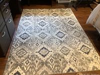Full view of the Art Deco area rug laid out on a hardwood floor, showing overall pattern and condition.