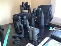 Overview of four pairs of binoculars with their cases arranged on a table.