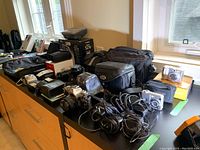 Overview of lot on black counter showing cameras, bags, chargers, cables
