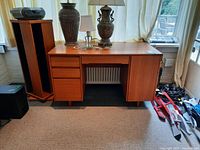 Front view of teak desk with drawers and cabinet, lamps and speakers on top