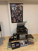 Full view of the audio setup including turntable, CD player, stereo tuner, vinyl 45s, CDs, and cassette tapes with storage containers and racks.