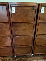 Front view of the four drawer wood file cabinet showing drawer fronts, lock, and attached keys.