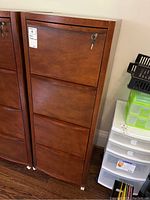 Front view of four-drawer wood file cabinet with key inserted in top drawer lock.