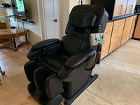Side view of black massage chair showing overall condition, reclining frame, and foot massager
