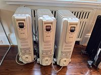 Three white Noma EW7507CE portable heaters placed side by side, showing overall size and design.