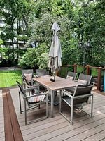 Full view of table, chairs and umbrella on deck from side angle