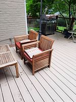 Two teak armchairs with cushions on deck alongside tea table