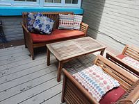 Teak coffee table on deck with surrounding patio furniture and cushions