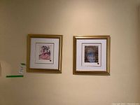 Two framed Tom Thomson prints hanging side by side on a beige wall, each with gold frames and white matting.